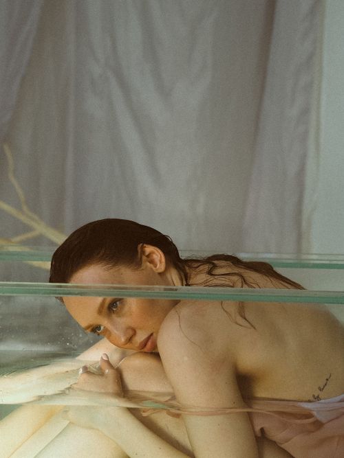 Free A contemplative woman enjoying a peaceful bath in a glass tub, creating a serene, calming atmosphere. Stock Photo