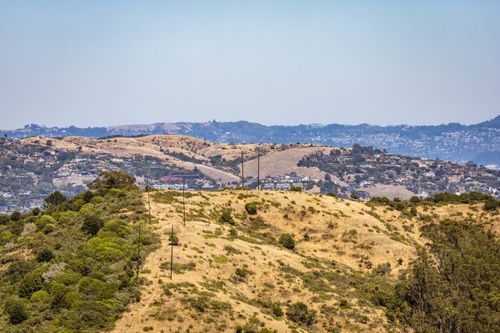 Free Breathtaking aerial landscape of rolling golden hills with residential areas in the distance. Stock Photo