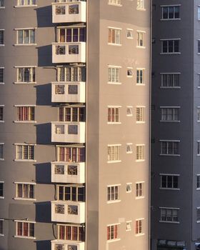 Close-up view of a sunlit residential building facade showing windows and balconies.