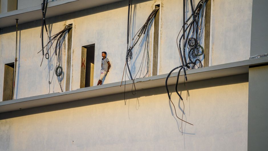 A man stands on a building floor with exposed cables at a construction site.