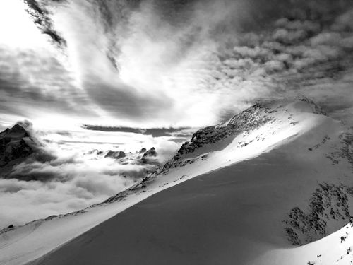 Free A stunning black and white photo of snow-covered mountains and cloudy skies. Stock Photo