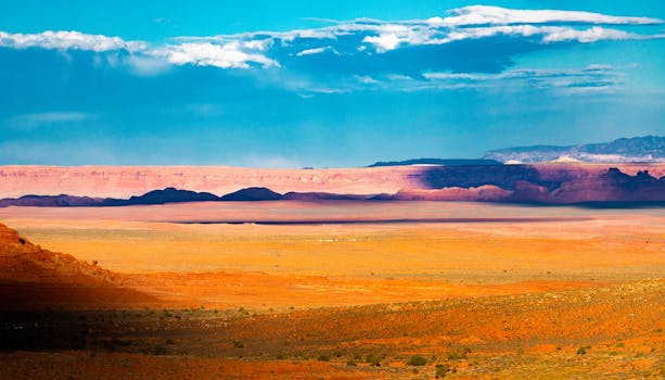 Breathtaking view of a desert landscape with vibrant colors and distant mountains under a bright blue sky.