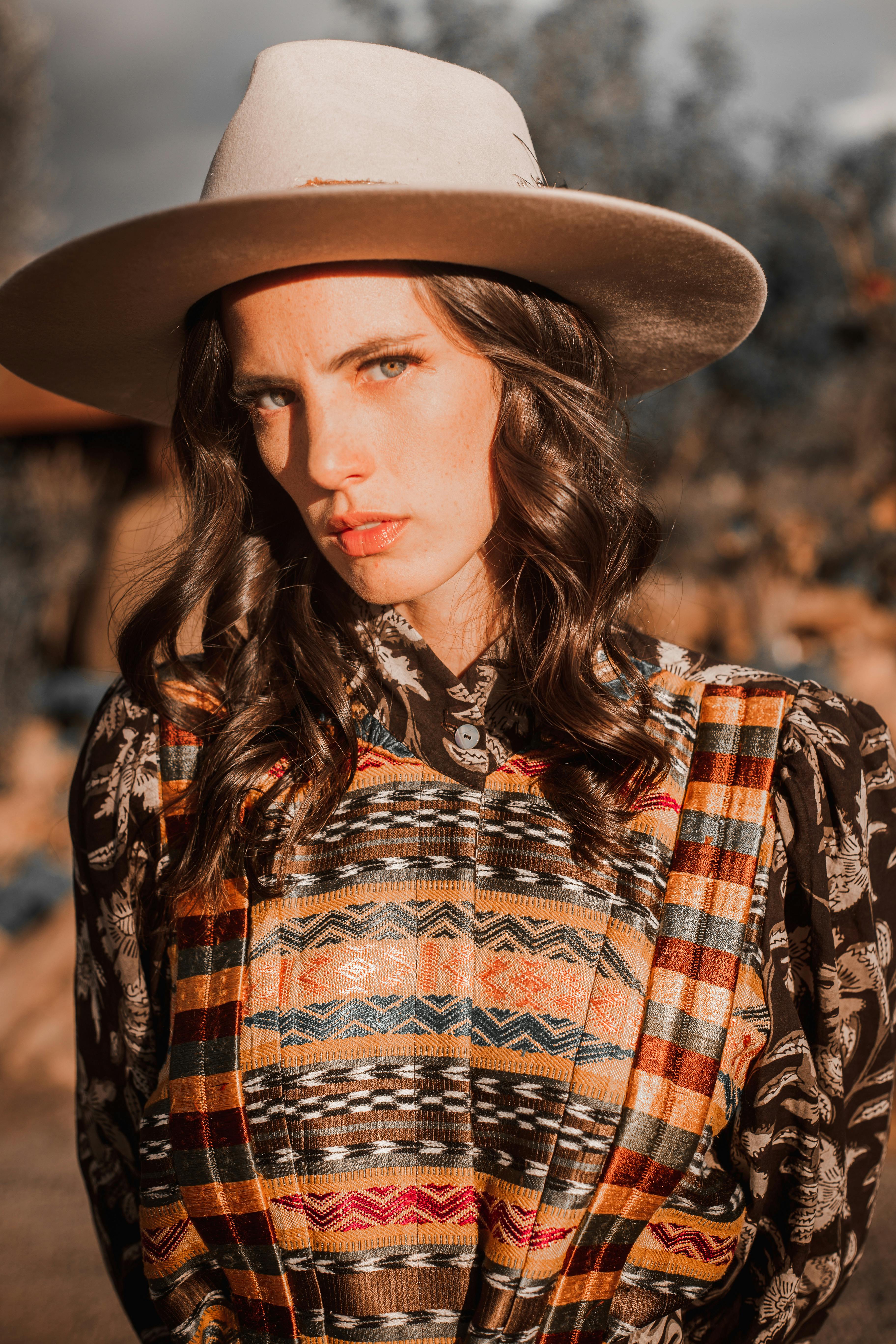 a beautiful woman with curly hair wearing cowboy hat while looking at the camera