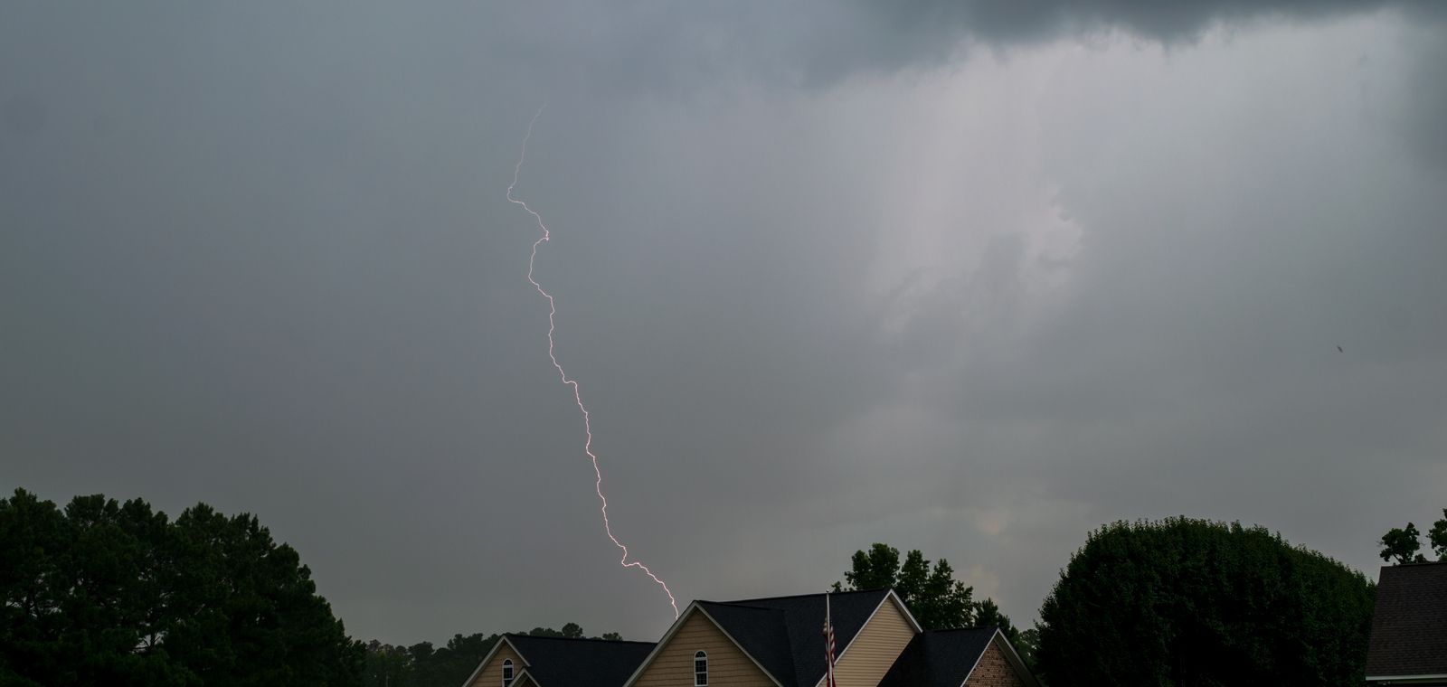 Lightning striking over suburban houses
