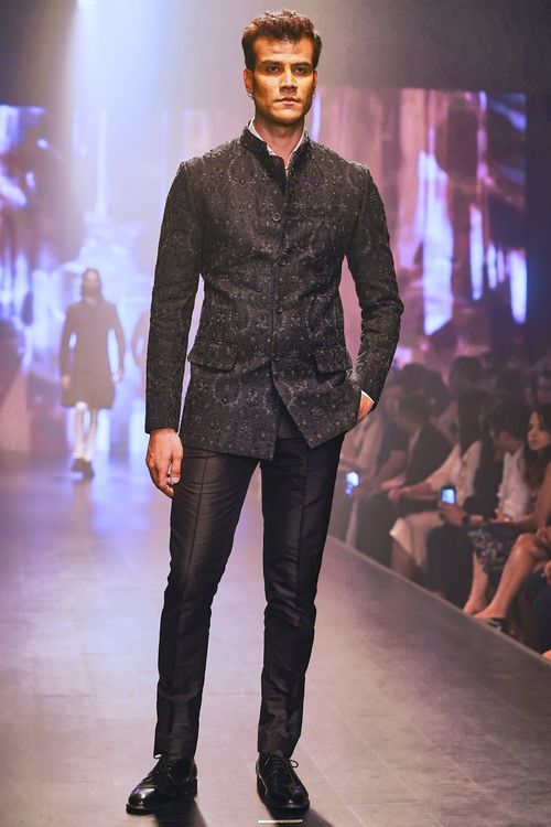 Free Male model in a black outfit walks the runway during a fashion show, showcasing modern style. Stock Photo
