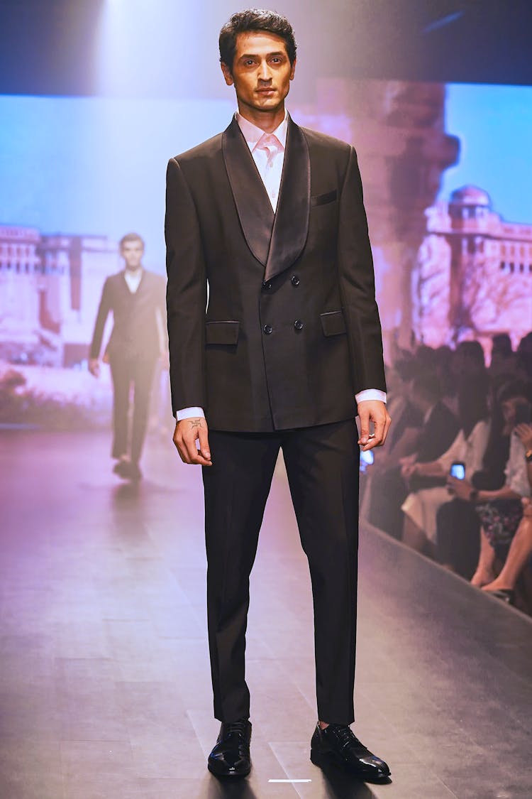 Male Model Wearing Black Suit And Pants While Standing On A Runway