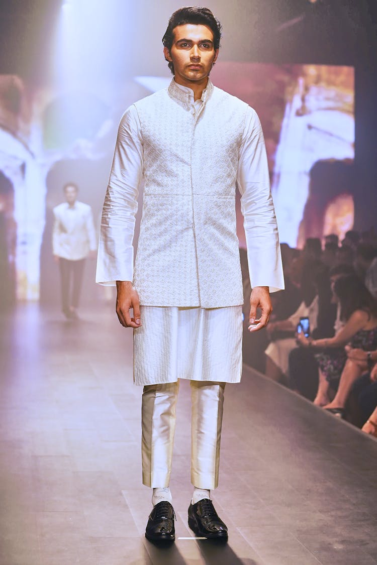 Model In White Outfit Standing On A Runway While Looking Afar