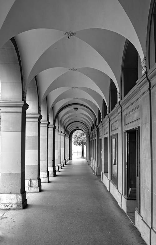 Grayscale Photo of a Corridor With Columns