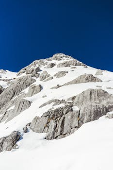Snowy mountain peak in Lijiang, China against a clear blue sky.