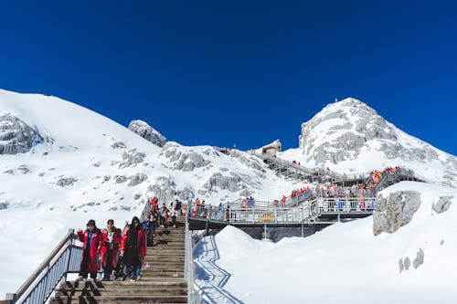 People Walking on a Wooden Boardwalk on the Snowy Mountains