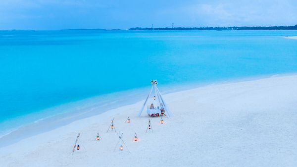 Romantic beach dinner setup by turquoise waters in the Maldives