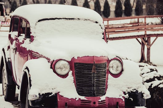 A snow-covered vintage car parked outdoors, capturing the essence of winter.