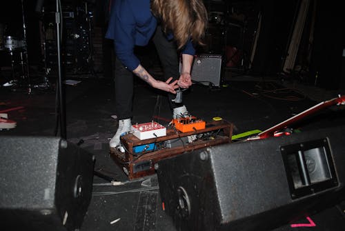 Person Standing Near Stage Speakers and Effect Pedal