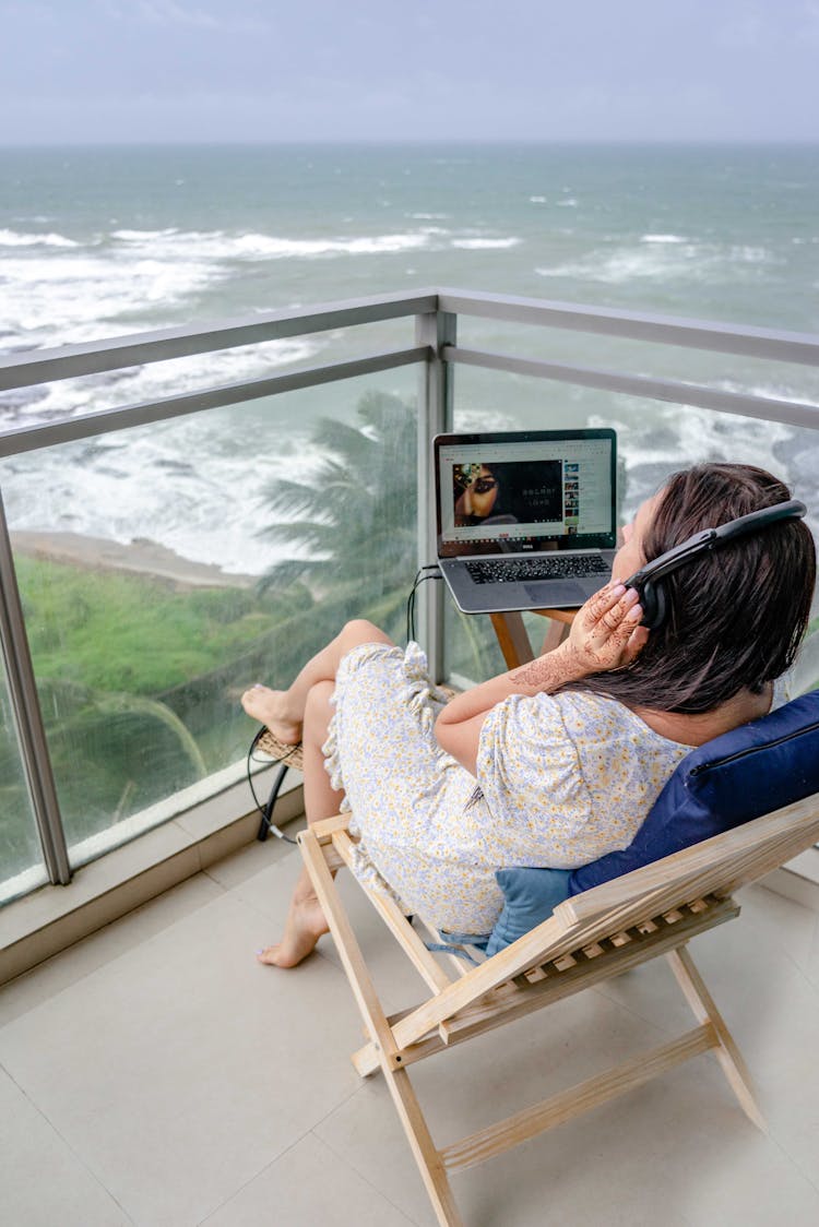 Woman Sitting With Laptop On Balcony