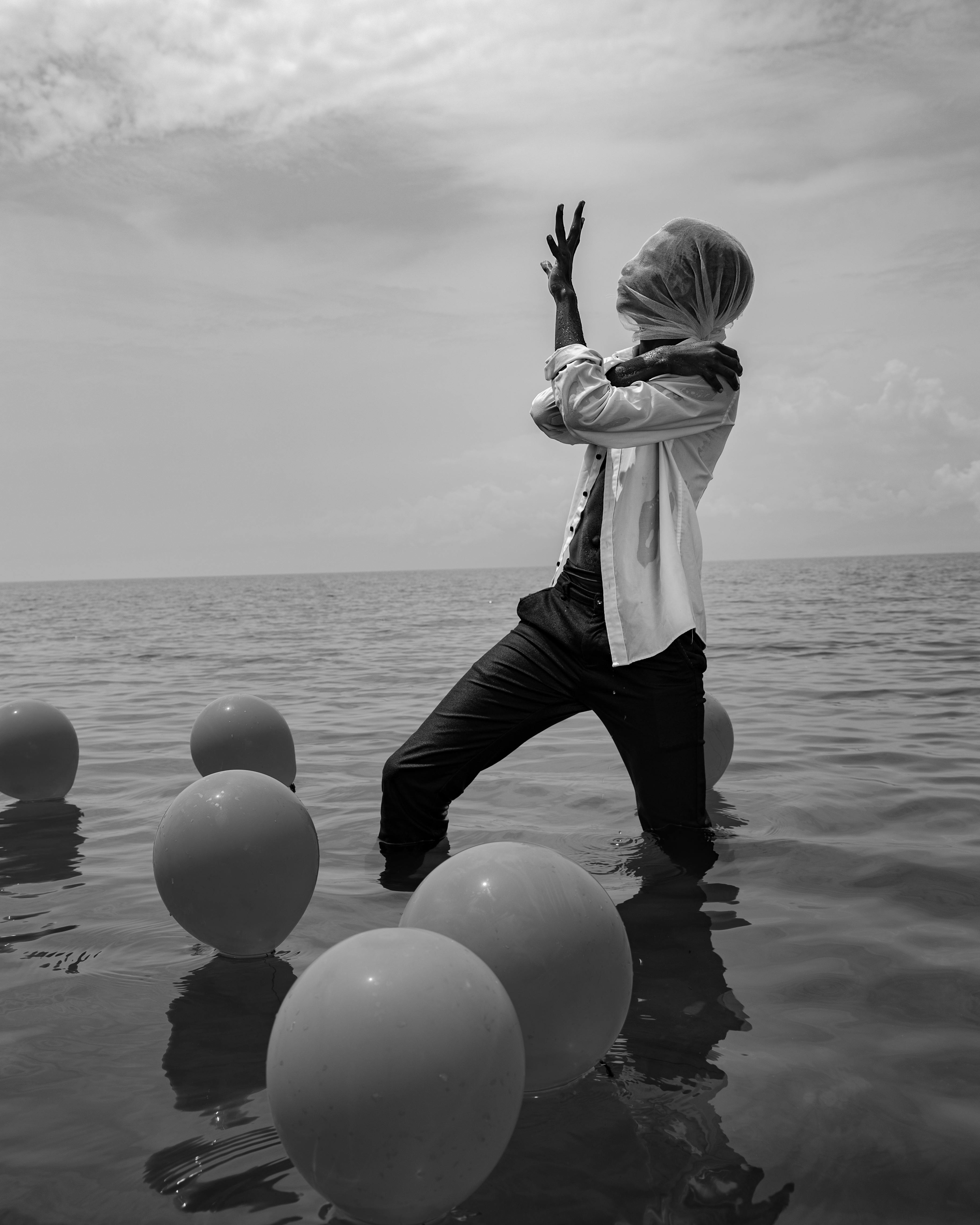A surreal black and white photo of a person with balloons in Lake Tanganyika, Burundi.