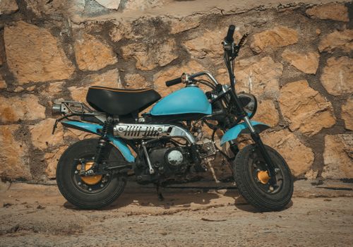 Free A parked vintage blue dirt bike stands against a textured stone wall on a sunny day in Zakynthos, Greece. Stock Photo