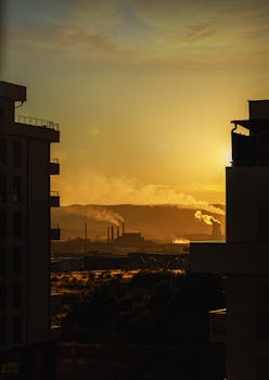 Stunning cityscape silhouette of Pristina during golden hour with industrial skyline and sunset.
