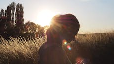 日落时分，草地上一个人使用手机的剪影，捕捉了大自然的美丽