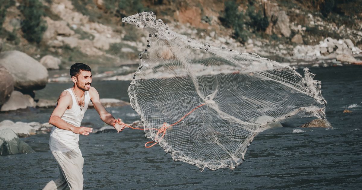 A fisherman casting a net into the sea, representing the moment a liquidity grab clears a level