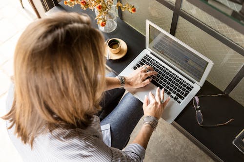 Person Sitting While Typing on Gray Laptop