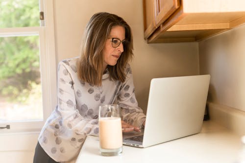 Vrouw Met Behulp Van Grijze Laptopcomputer In De Keuken