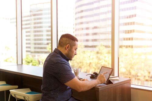 Free Side view of a man using a tablet in a bright office with city view. Stock Photo