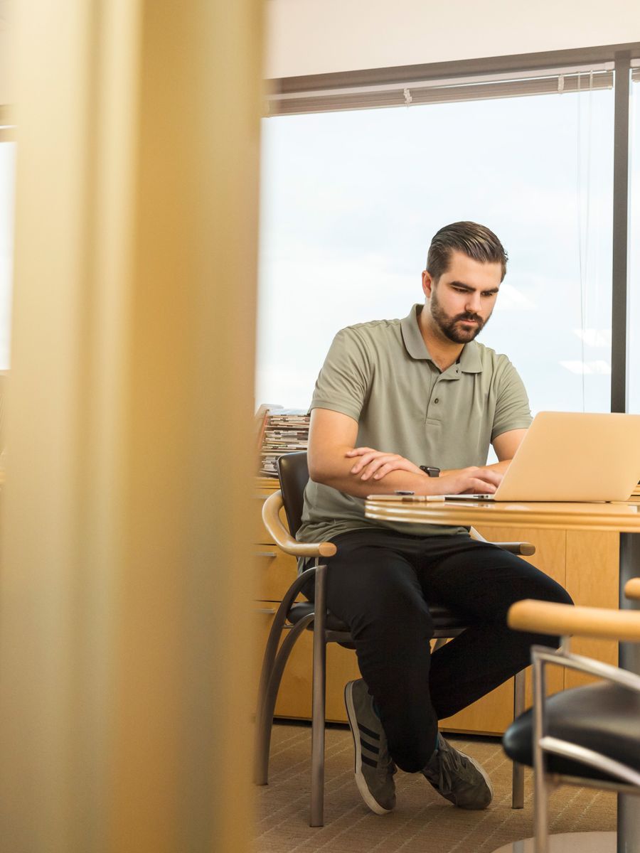 Man seated at a table working on a laptop