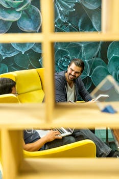 Two professionals in a modern office setting, discussing work in a relaxed environment surrounded by vibrant decor.