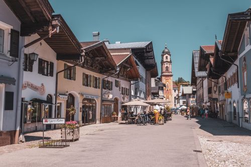 Free A picturesque street in Mittenwald, Bavaria, showcasing traditional architecture and vibrant summer life. Stock Photo