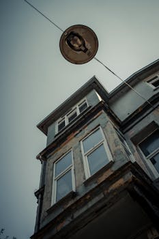 A dramatic low angle view featuring a streetlamp and an aged urban building.