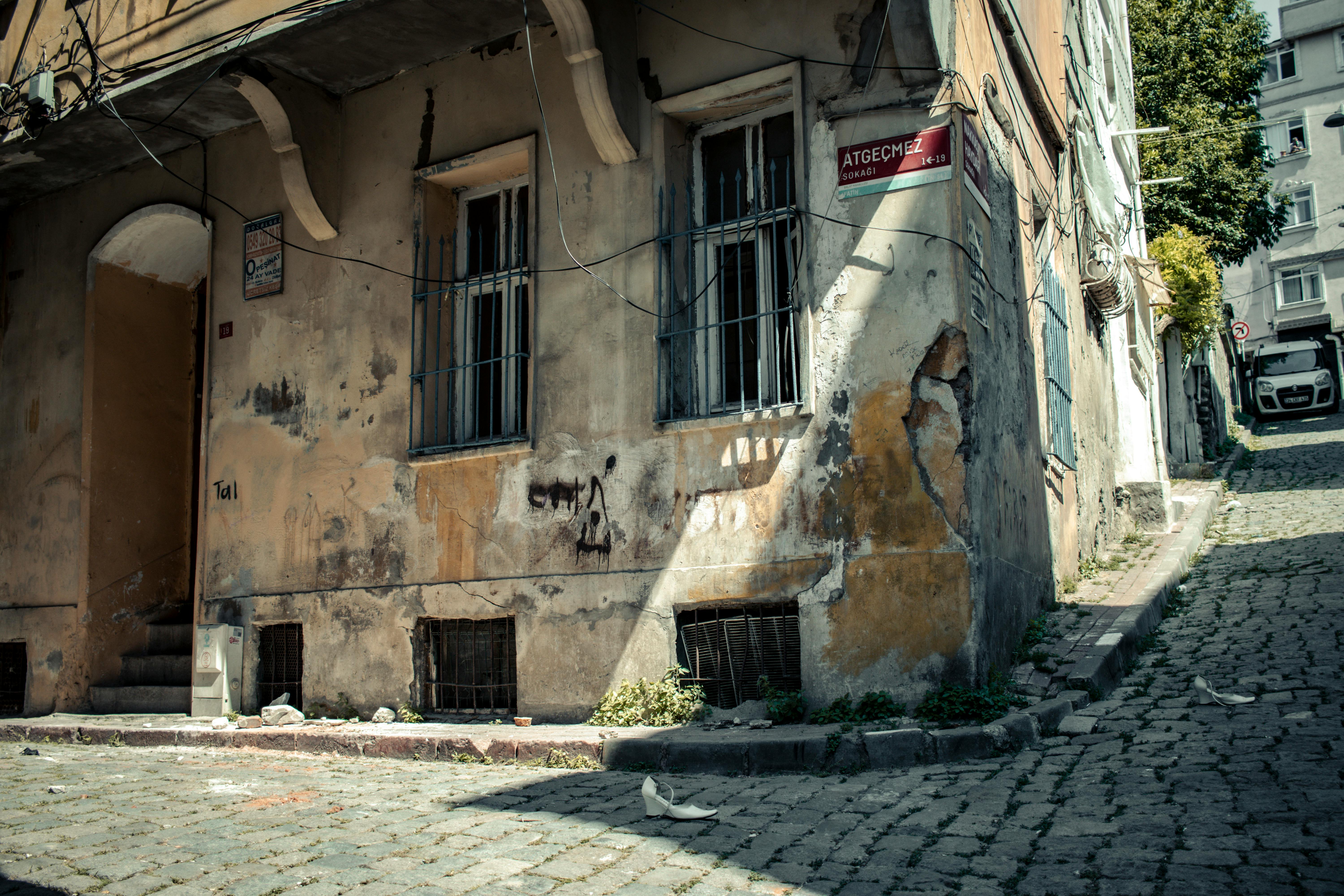 Free A decaying residential building with weathered facades on a cobbled street corner in daylight. Stock Photo