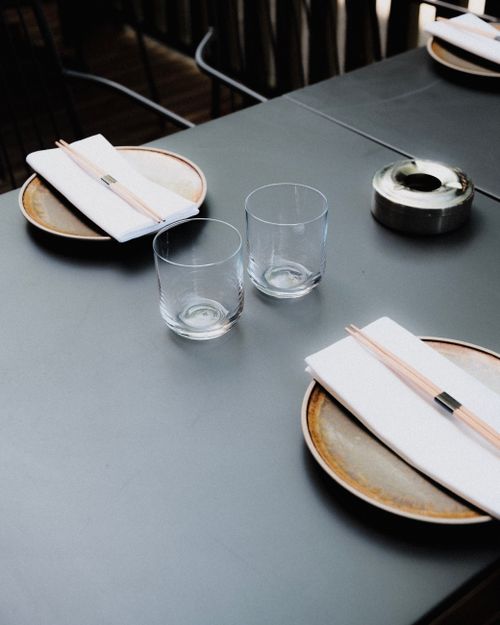 Free Minimalist table setting with chopsticks, glasses, and napkins on plates. Ideal for dining imagery. Stock Photo
