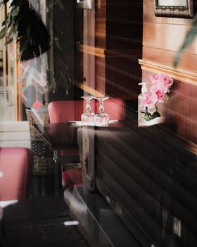 Stylish interior of a restaurant with red chairs, wooden walls, and glass reflections.