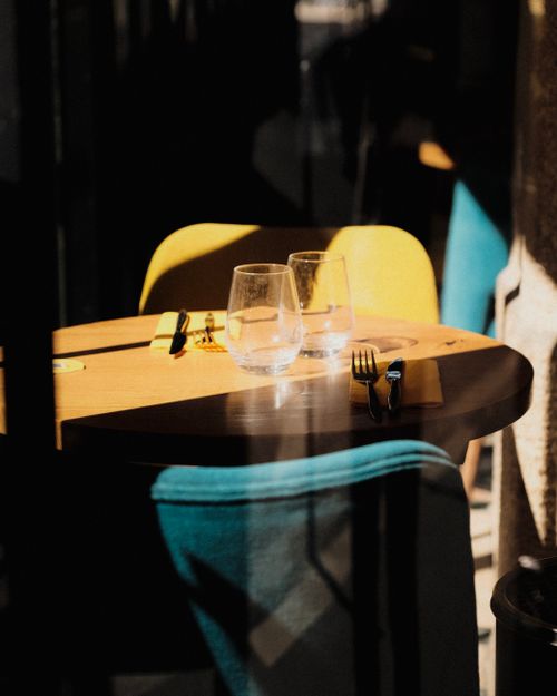 Free A cozy dining table with chairs in sunlight, featuring a beautiful place setting in a modern restaurant. Stock Photo