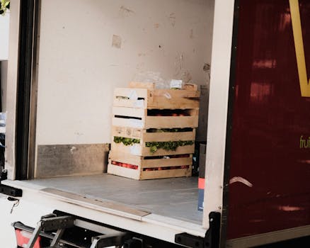 A wooden crate with fresh vegetables loaded inside a delivery truck, ready for transportation.