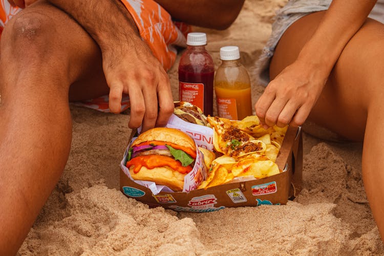 Man And Woman Reaching For Food On Beach