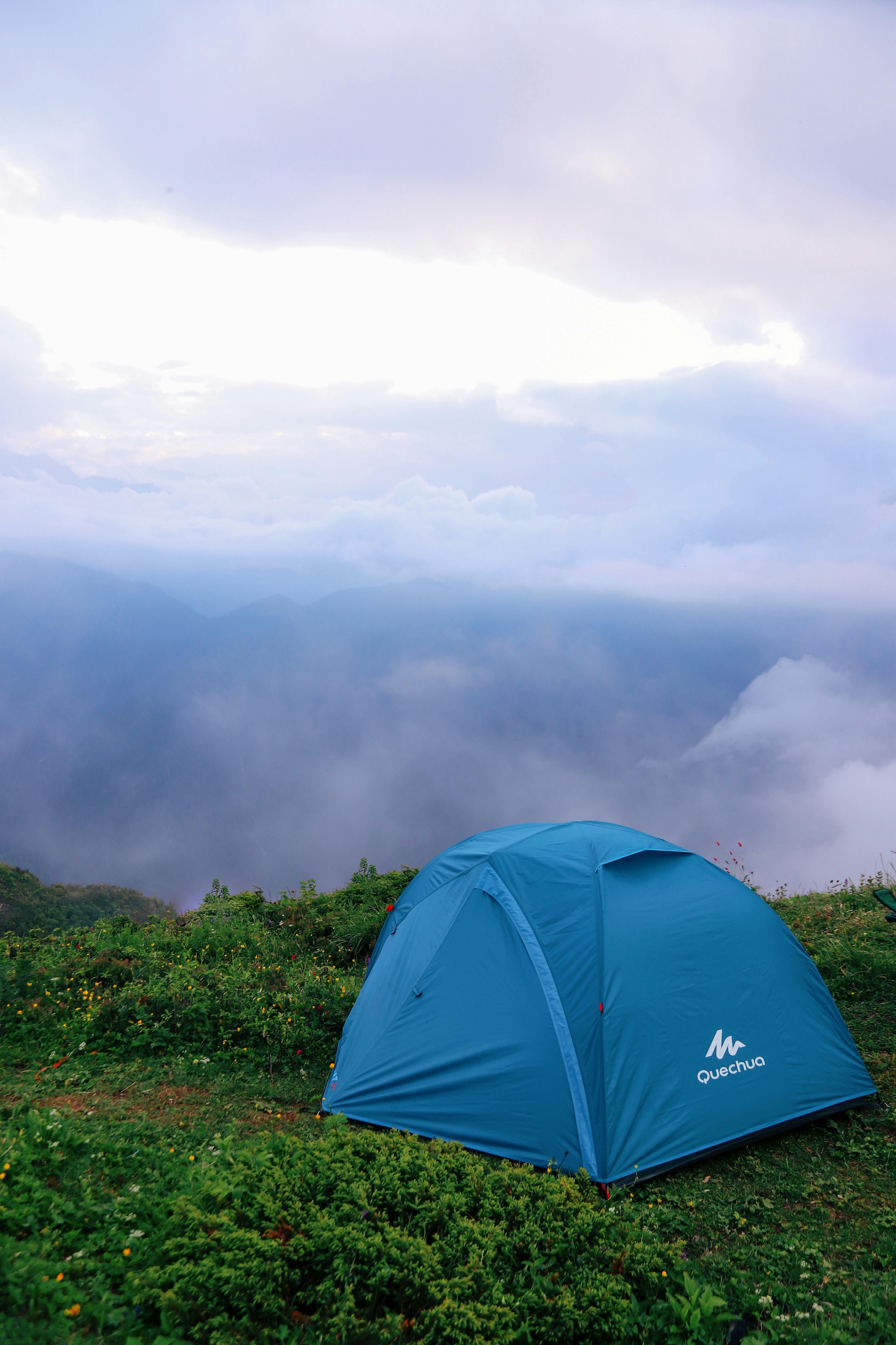 Dark storm clouds over a forest campground with a tent and tall pine trees
