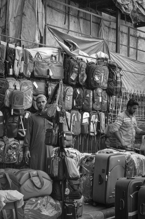 Free Black and white photo of vendors selling bags at an outdoor market stall. Stock Photo