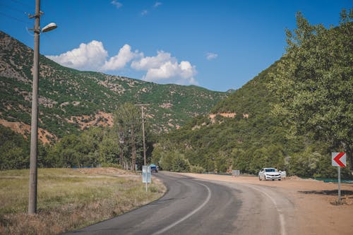 Moving Cars on the Road Near Green Mountains