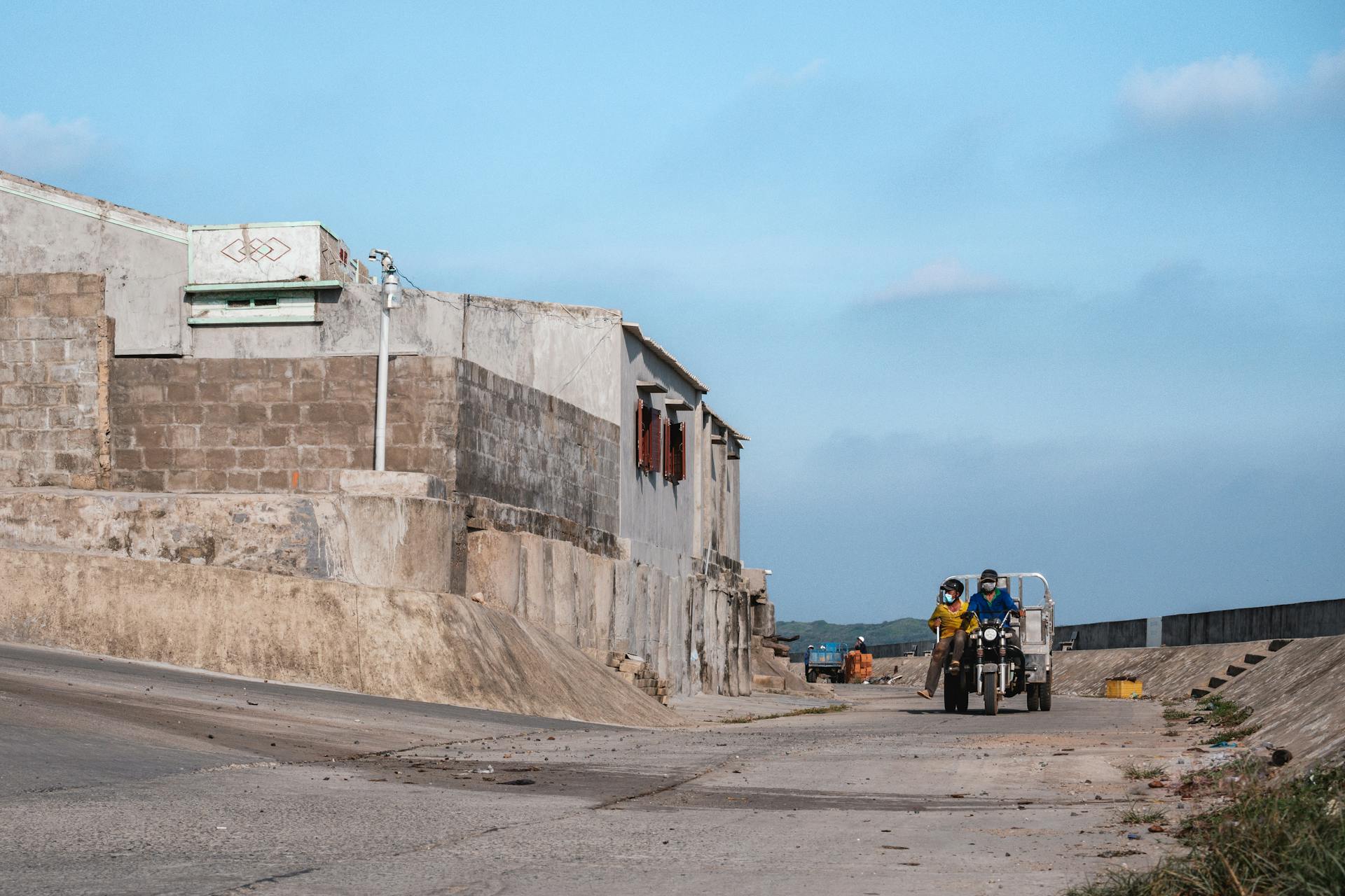 A vibrant street scene featuring two people riding a motorcycle on a sunny day.