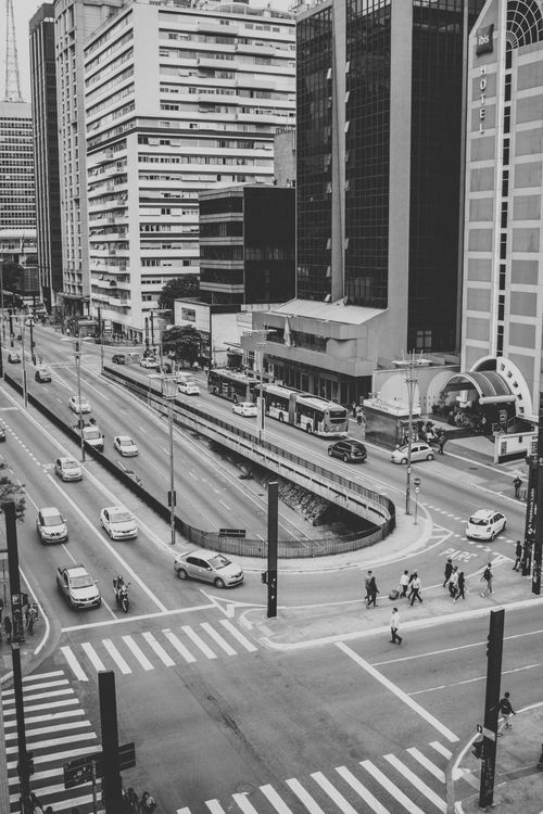 Free Black and white cityscape of a busy street with cars and pedestrians. Stock Photo