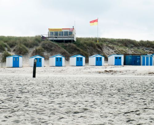 Free Charming beach huts with blue doors line a sandy shore in the Netherlands. Stock Photo