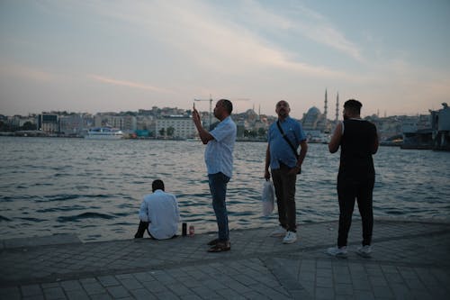 Men Standing near Body of Water during Sunset