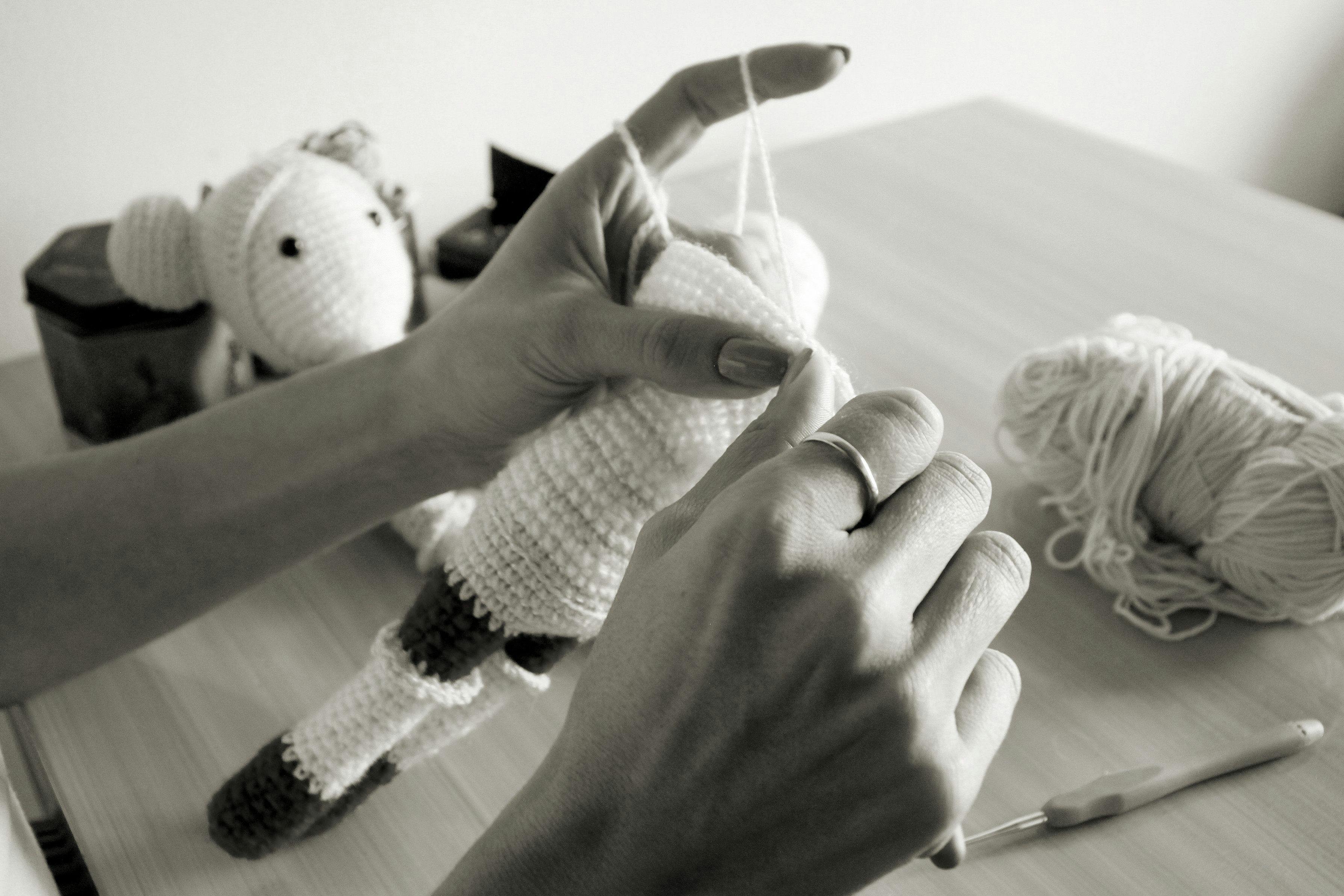 Hand crafting a crochet toy in a black and white setting, showcasing detailed needlework.