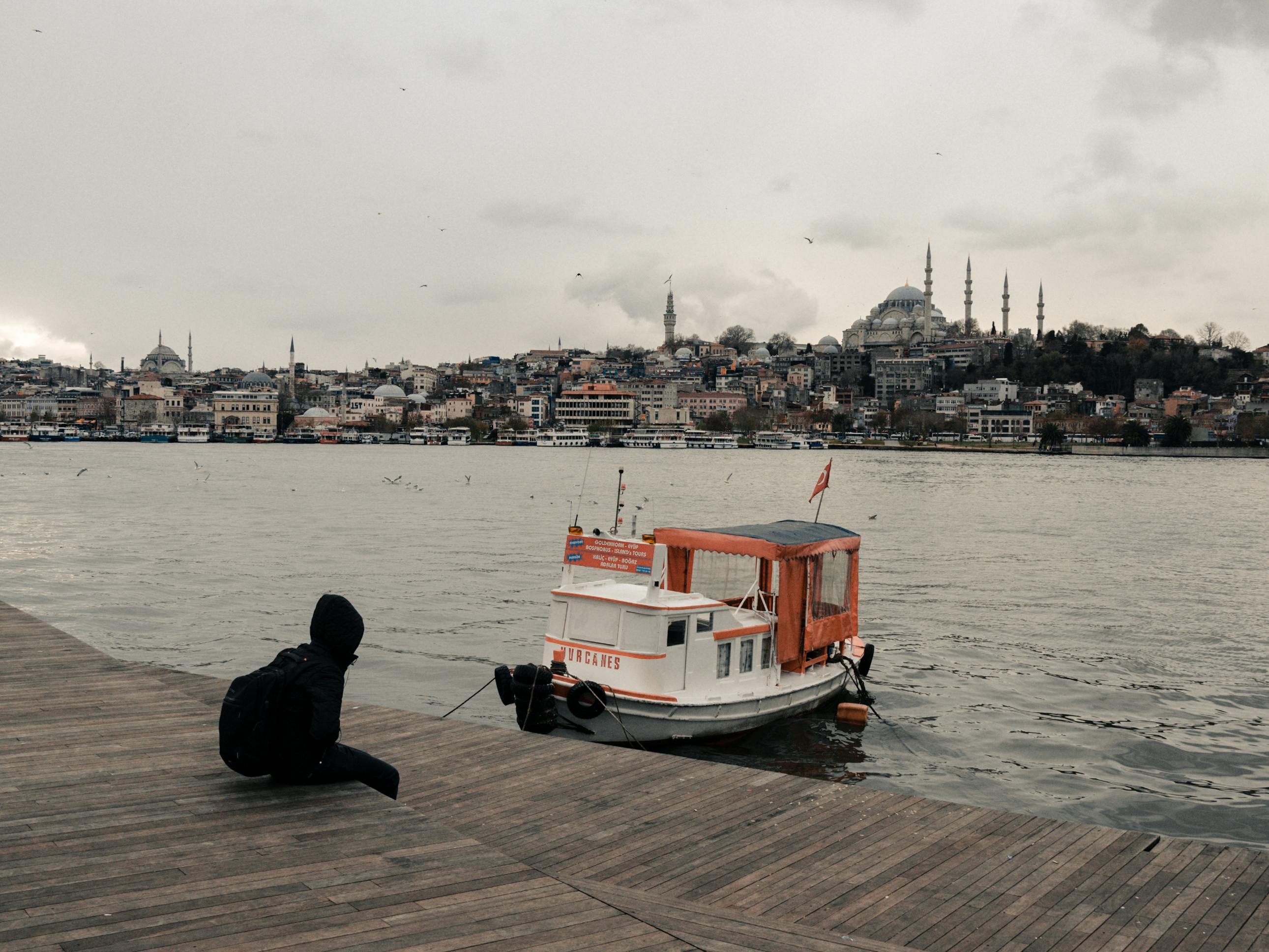 Gratuit Personne Portant Un Sweat à Capuche Noir Et Un Sac à Dos Assis Sur Un Quai En Bois Photos