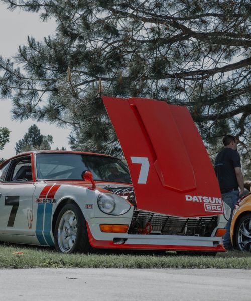 Free A vintage Datsun racecar with the hood up, displayed at an outdoor car show. Stock Photo