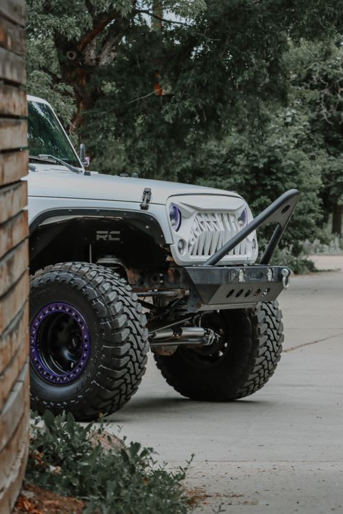 Free Close-up of off-road vehicle parked by a brick wall surrounded by greenery outdoors. Stock Photo