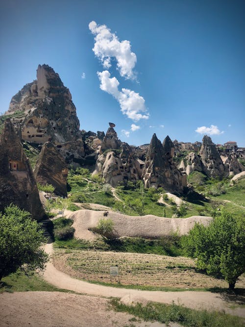 Rock Formations and Green Grass Under White Clouds on a Blue Sky