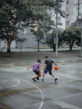 Two men engaging in a lively basketball game outdoors in Armenia, Quindío, Colombia.