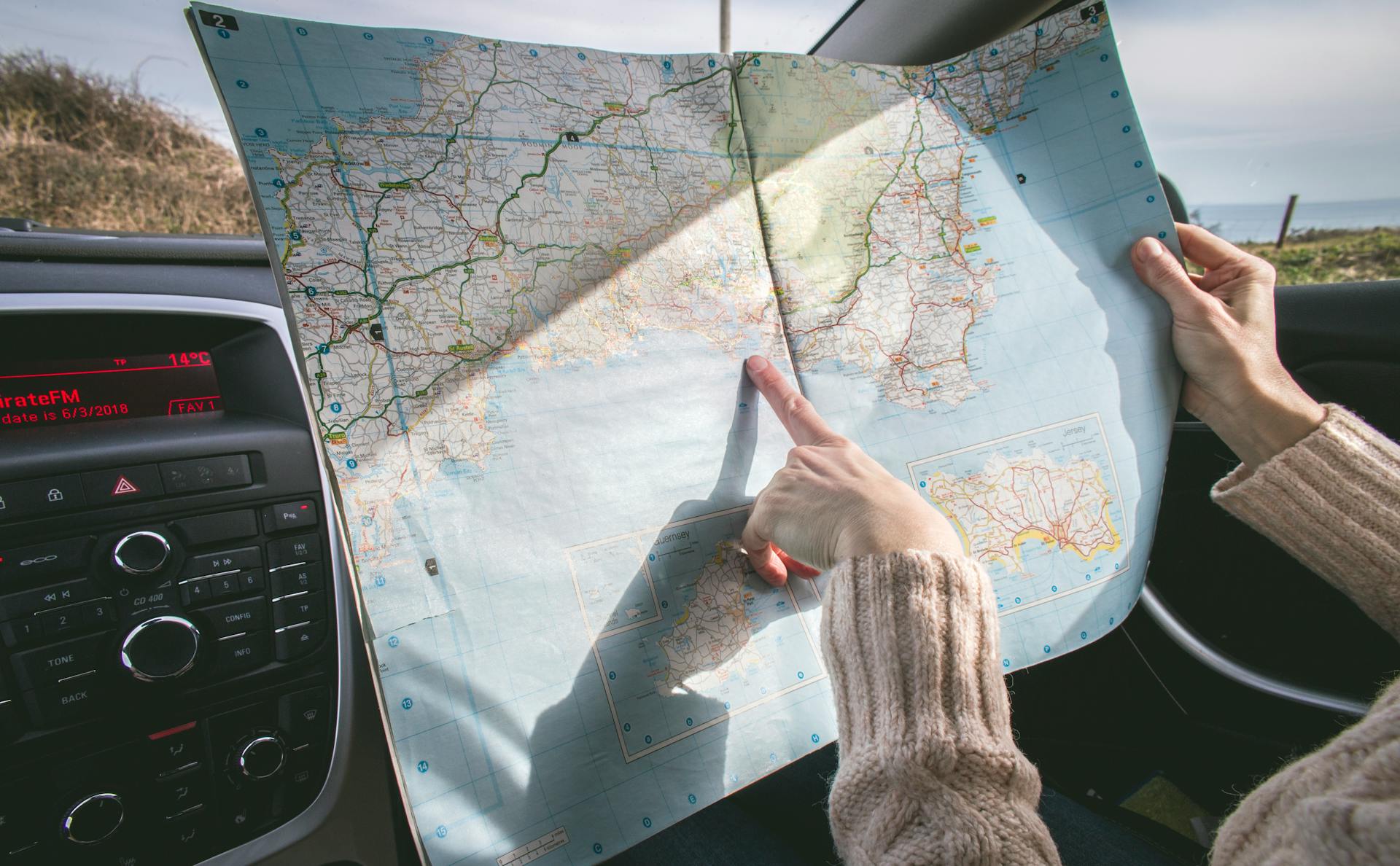 Person Wearing Beige Sweater Holding Map Inside Vehicle